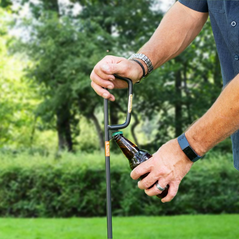 Man opening a bottle of beer with bottle opener located at base of handle of a fire poker