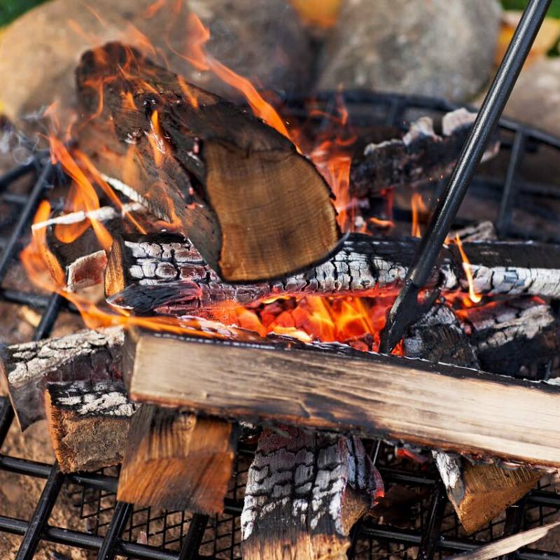 Tip of Walden blow through stoker poker poking logs in a ground fire pit