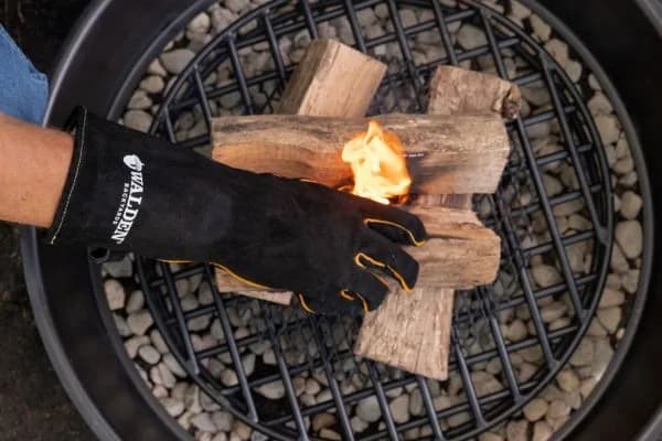 Leather fire gloves resting on a stack of split, seasoned firewood