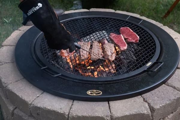 Steaks searing over live fire on a Walden grilling grate