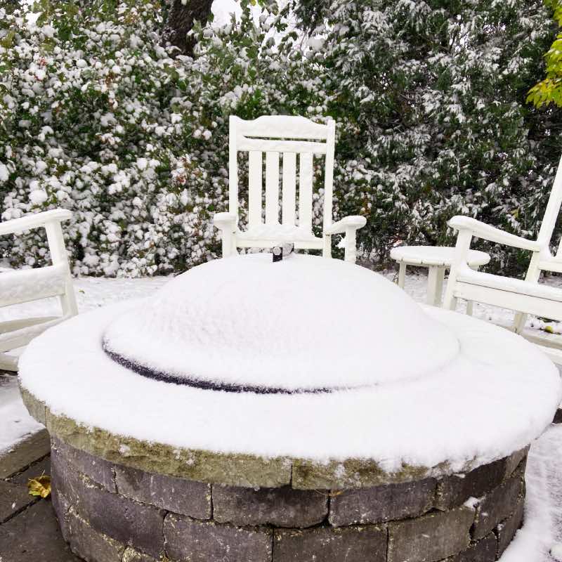 Snow covered fire pit lid keeps moisture out of the fire pit.