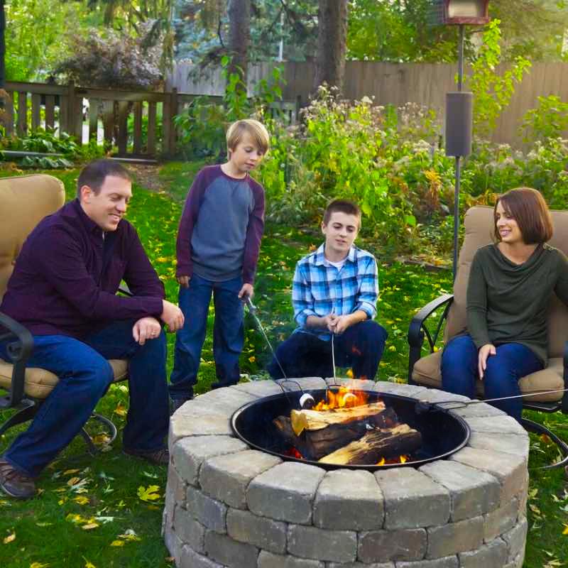 family roasting marshmallows gathered around fire ring surrounded by blocks