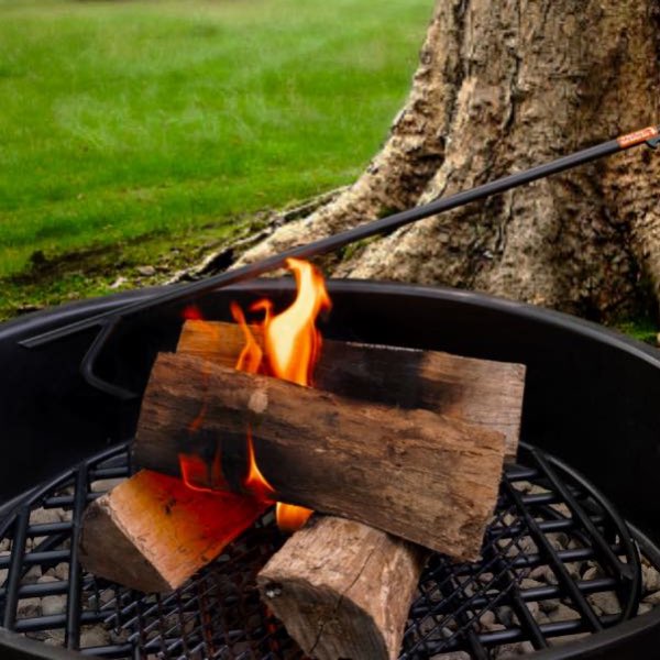 Fire poker grabbing and pulling logs inside a fire pit ring with a fire grate
