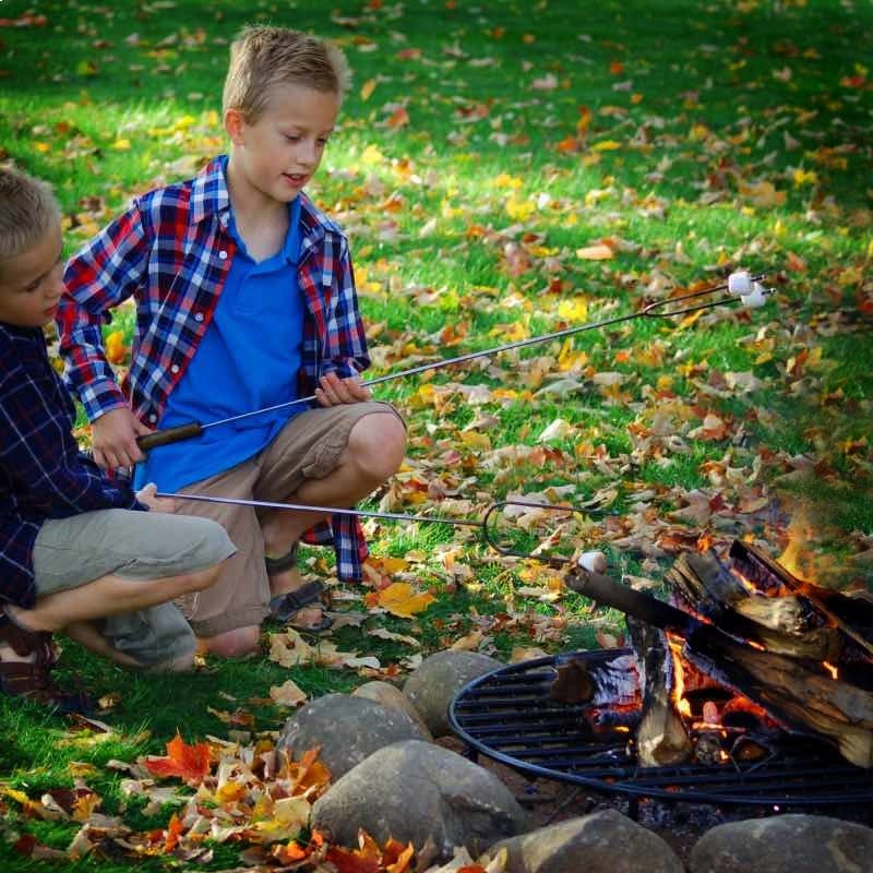 Children roasting marshmallows over fire burning on sturdy steel fire pit grate.