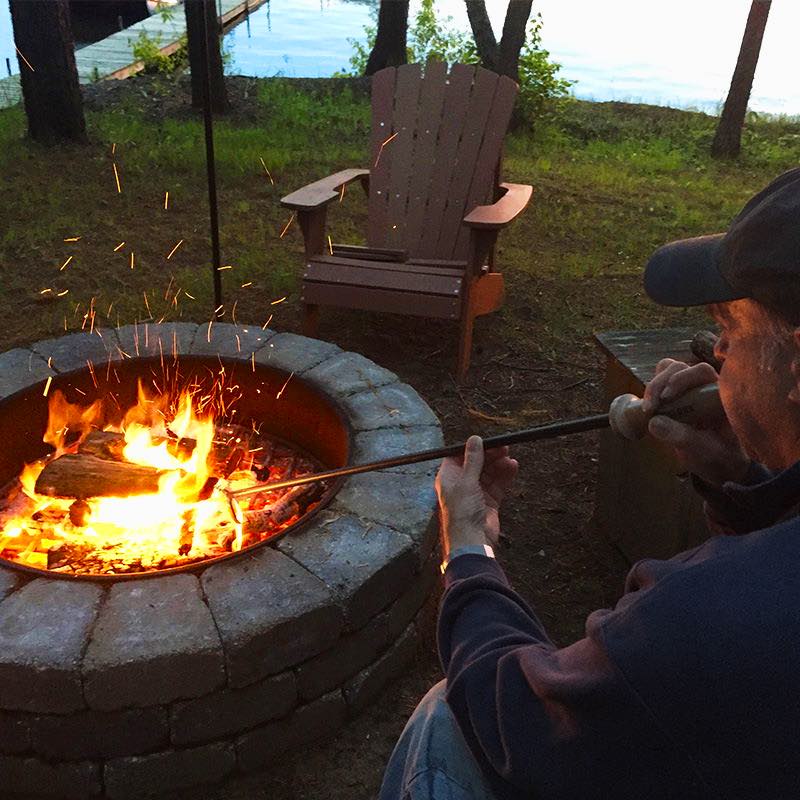 Man blowing air into valve of Walden blow through stoker poker to revive fire